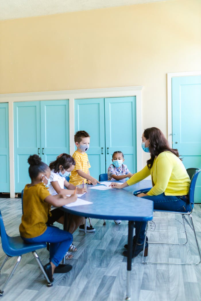Children learning with a teacher wearing masks in a vibrant classroom.